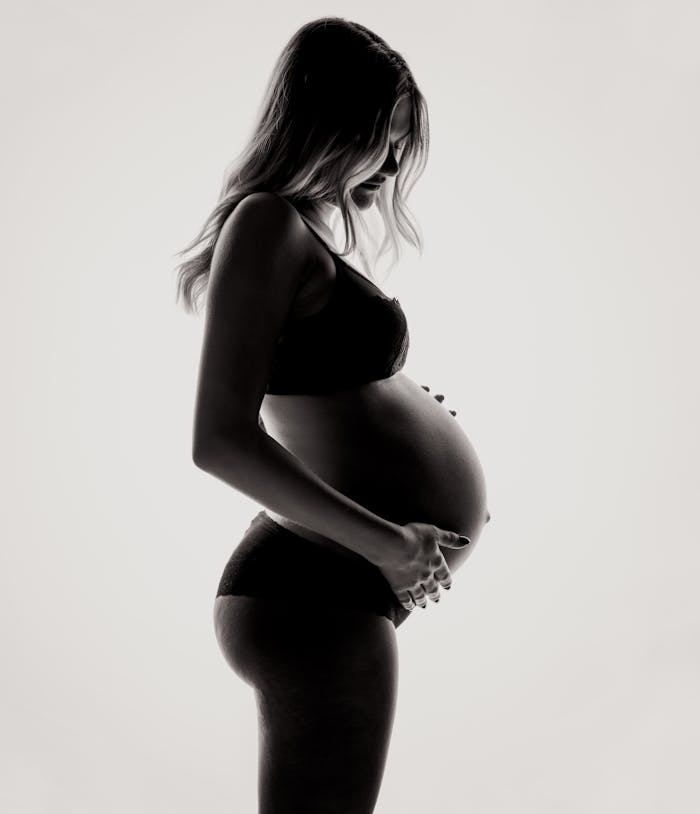 Silhouette of a pregnant woman in lingerie, expressing motherhood and contemplation.